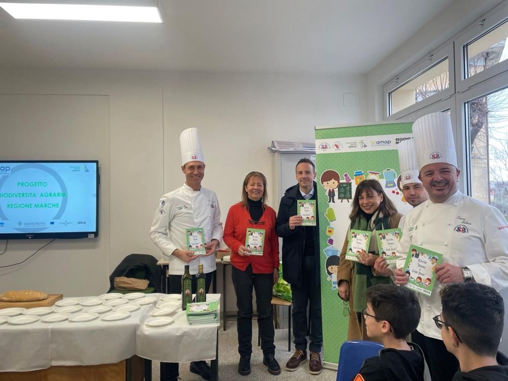 L'immagine ritrae il momento della presentazione della pubblicazione con il presidente Rotoni, i  cuochi e le insegnanti